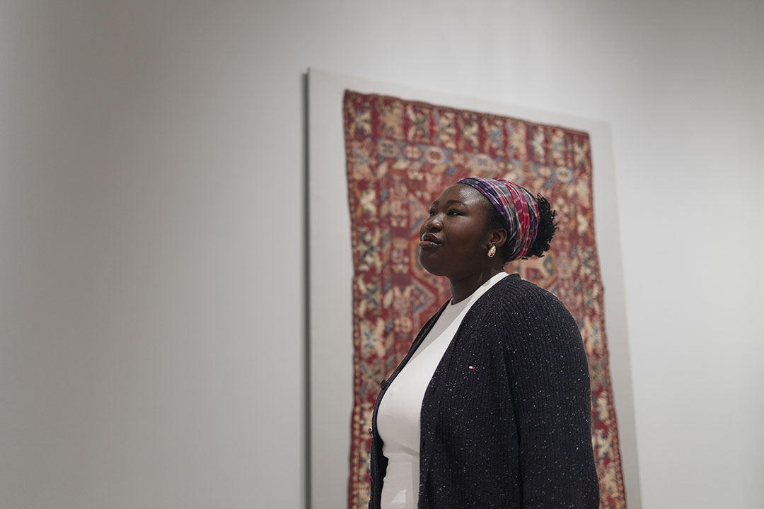 Inioluwa Jobi standing in front of a quilt at the GW Textile Museum