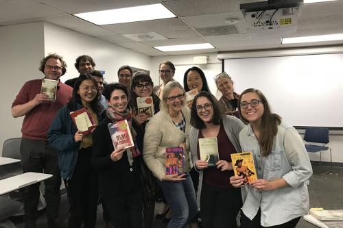 Students and staff posing and holding up books