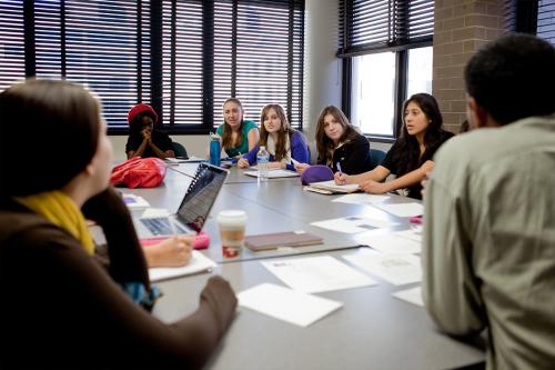 A group of honors students sit around a table talking